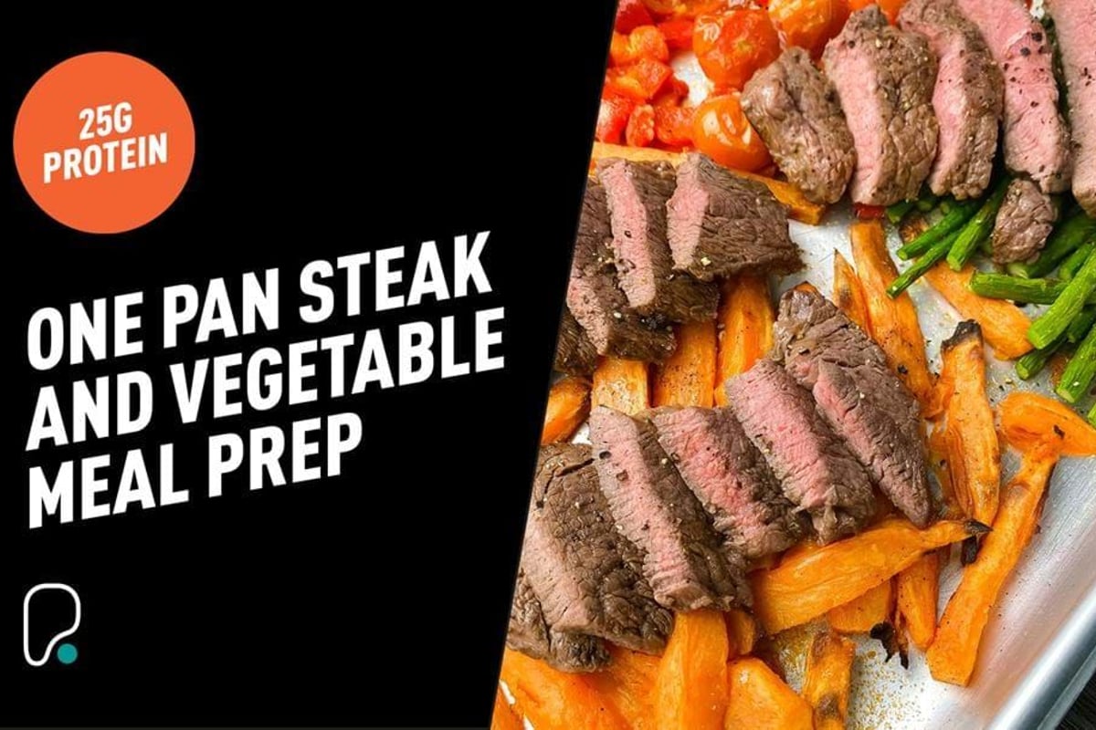 Sliced steak, roasted carrots, green beans, and cherry tomatoes on a baking tray