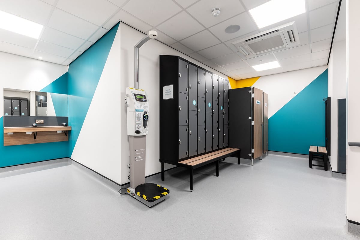 PureGym London Feltham: Lockers, benches, vending machine in a changing room area.