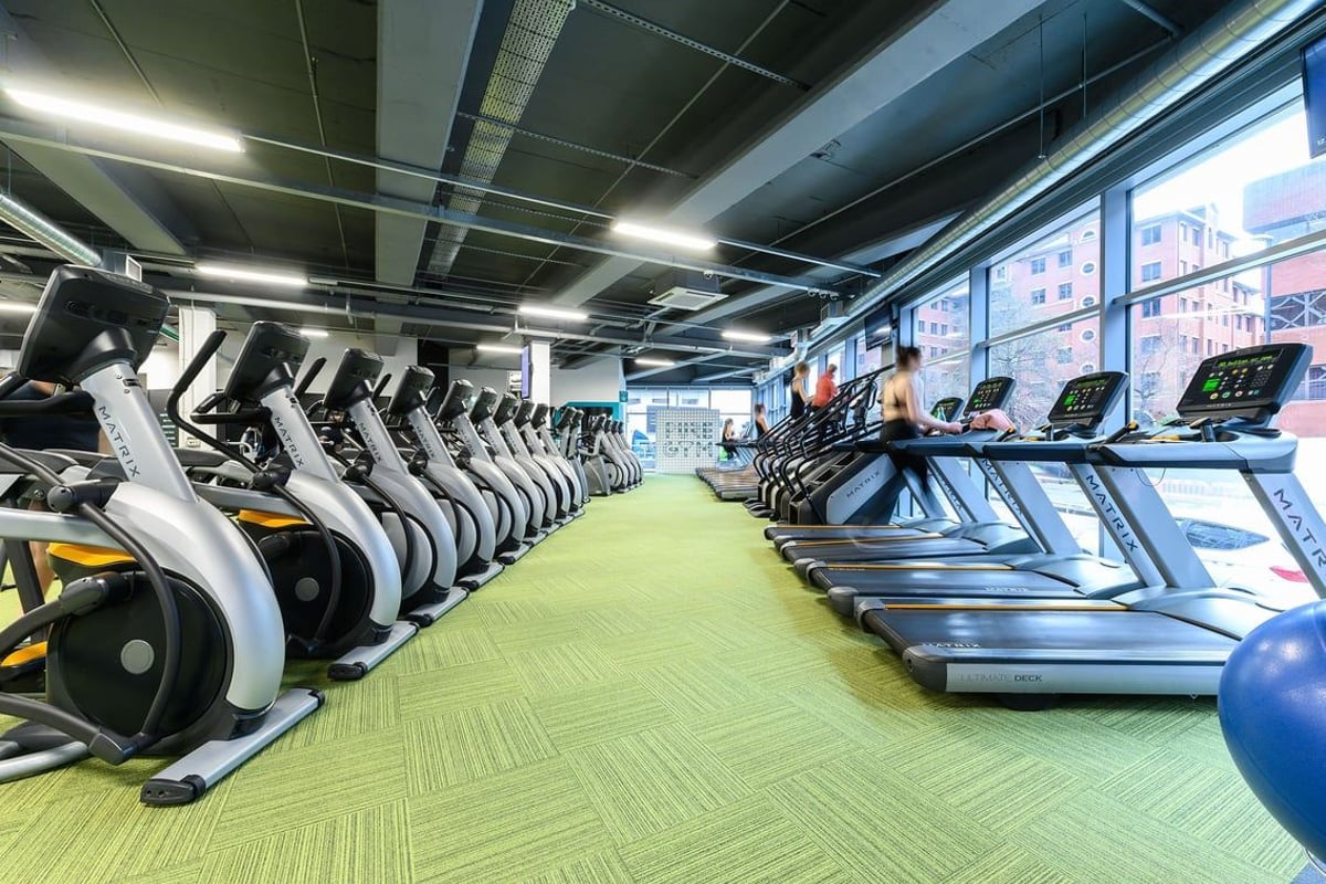 PureGym Leeds City Centre North: Rows of treadmills, exercise bikes and green flooring in a brightly lit gym interior.