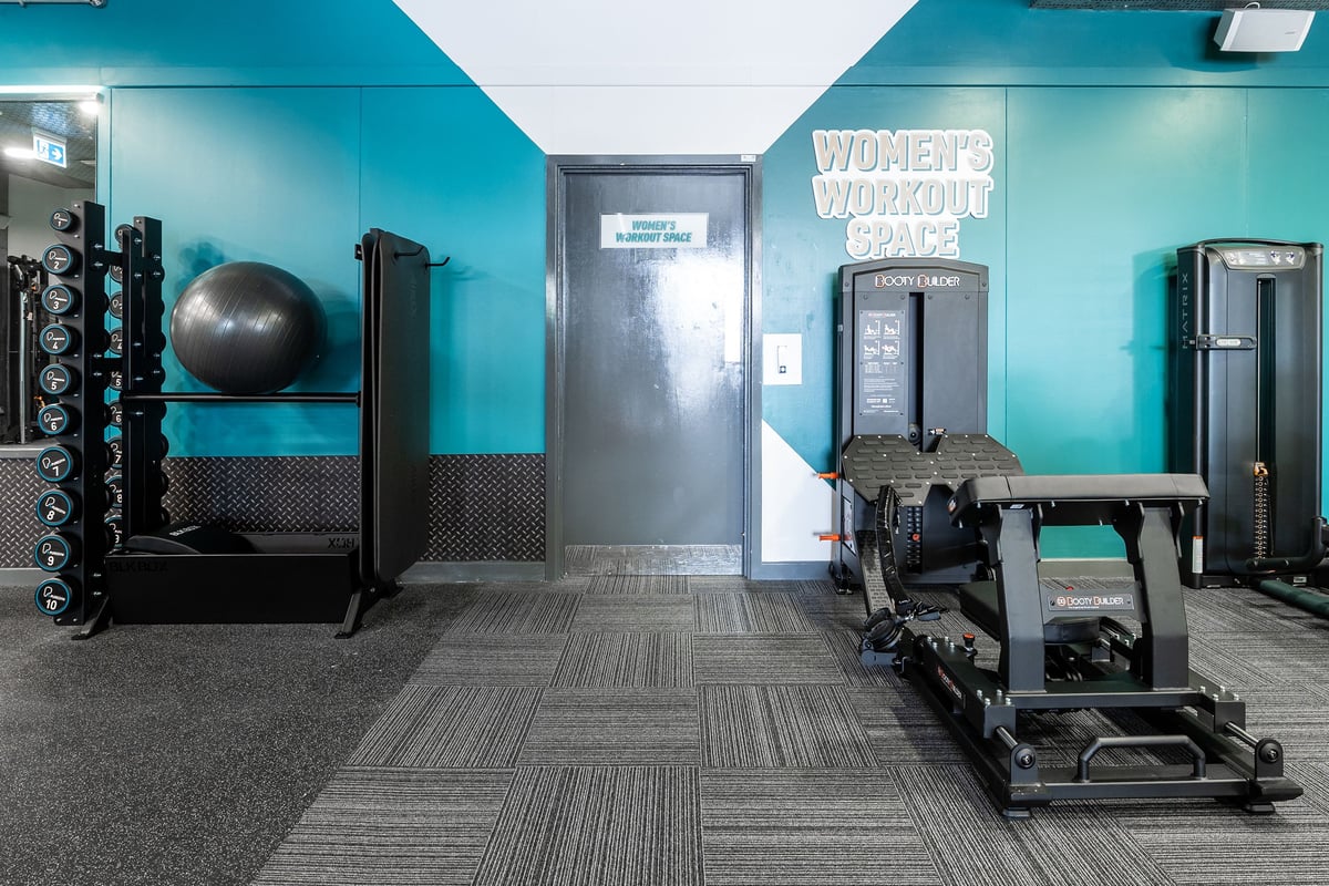 PureGym London Limehouse: Women's workout area with weight racks, exercise ball, patterned flooring, teal walls.