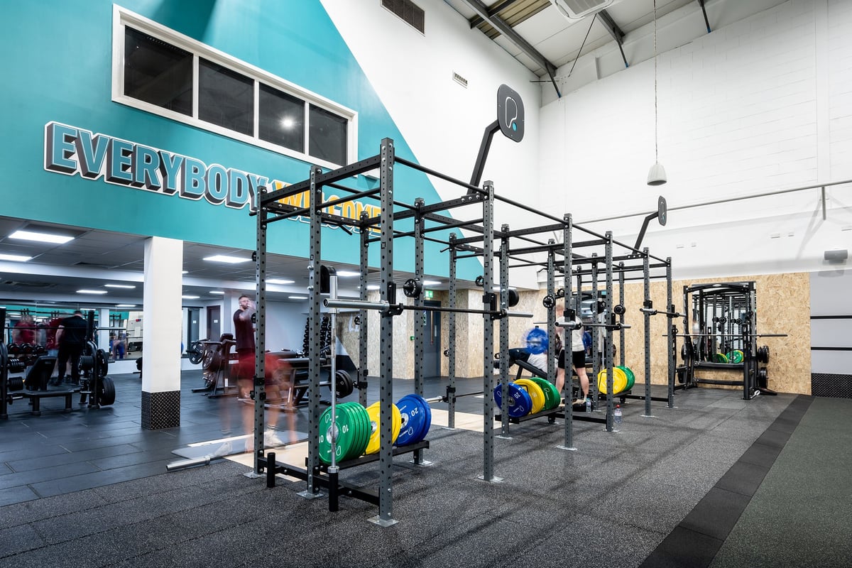 PureGym Newtownabbey: Rows of squat racks, exercise rigs, wall balls, and rubberized flooring in a gym space.