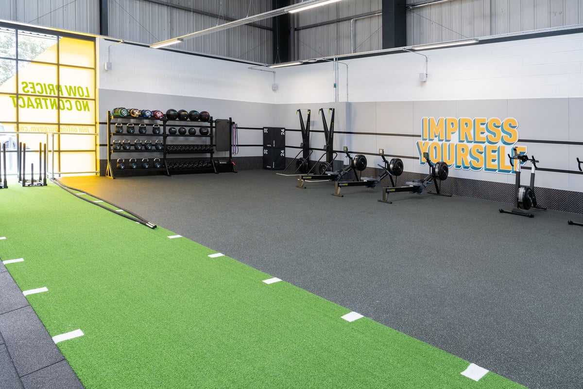 PureGym Dover: Weights racks, turf area, squat stands, rubberized flooring in a gym studio.