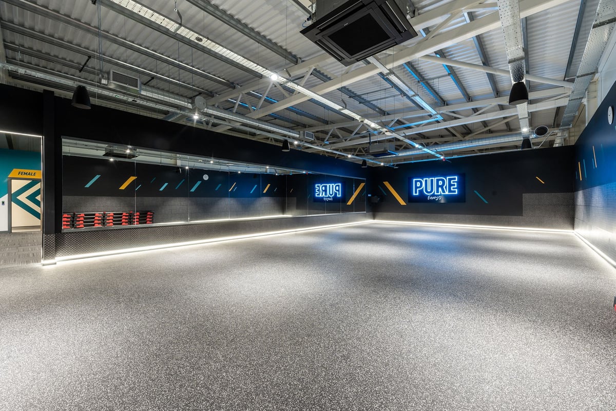 PureGym Barnsley: Enclosed fitness studio with rubberised flooring, angled wall graphics, and exposed ceiling beams