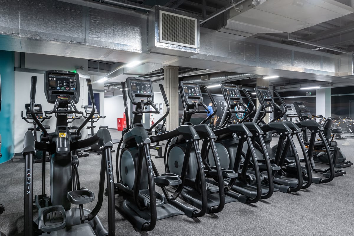 PureGym Liverpool Central: Rows of elliptical cross-trainers and treadmills in a basement gym setting.