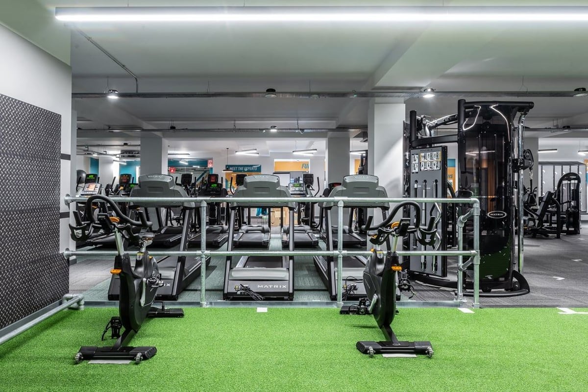 PureGym London Twickenham: Weight racks, resistance machines, artificial turf, free weights scattered on the gym floor.