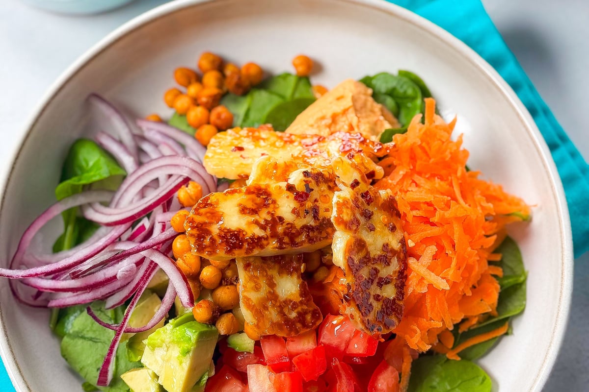 Salad bowl with grilled halloumi, spinach, shredded carrot, tomato, avocado, red onion