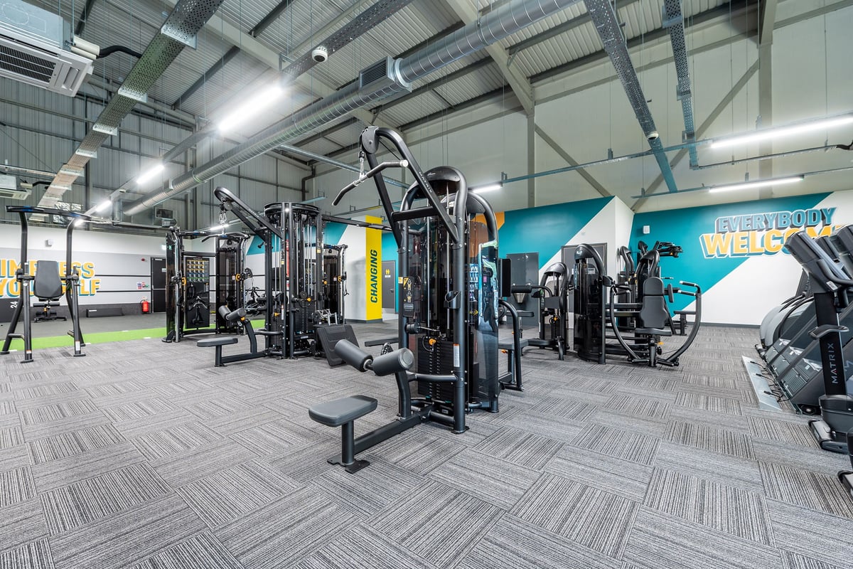 PureGym Sudbury: Cable machines, weight racks, benches, rubberized floor tiles inside a commercial gym facility.