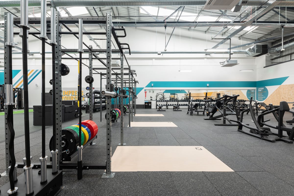 PureGym Southport: Racks, weights, benches, rubberized flooring in a fitness studio with teal accents.