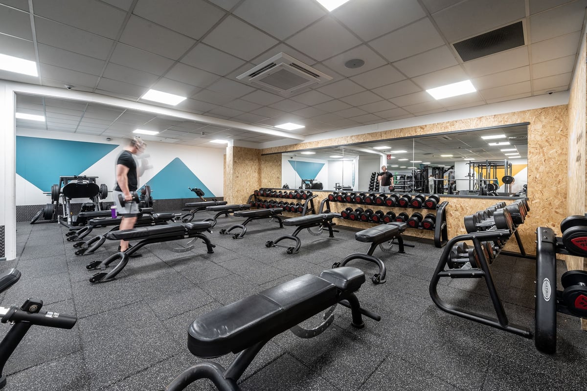 PureGym Epsom: Rows of weight benches, resistance machines, and rubberized flooring in a gym studio setting.