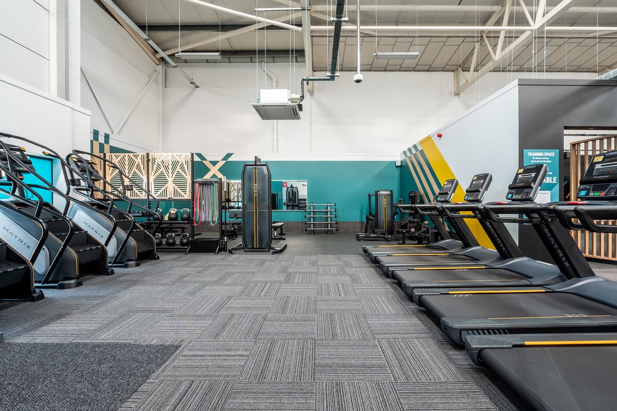 PureGym Bridgend: Rows of treadmills, ellipticals, weight machines, and free weights in a modern gym setting.