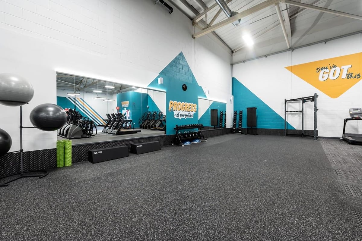PureGym Taunton: Rows of weight racks, medicine balls, stepping platforms in teal and yellow colours, rubberised flooring.