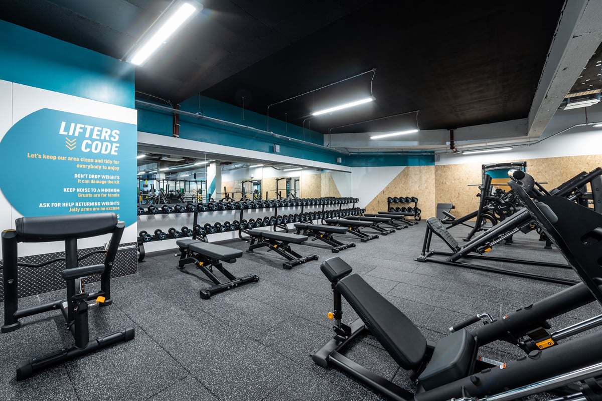 PureGym London Beckenham: Rows of strength equipment, benches, and weights on rubberized gym flooring under bright lighting.