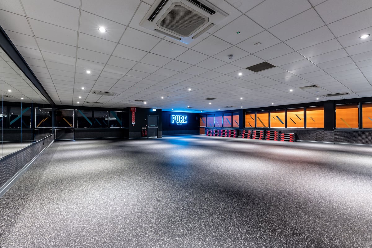 PureGym Livingston: Empty lobby area with tiled floors, modern lighting, and digital signage.