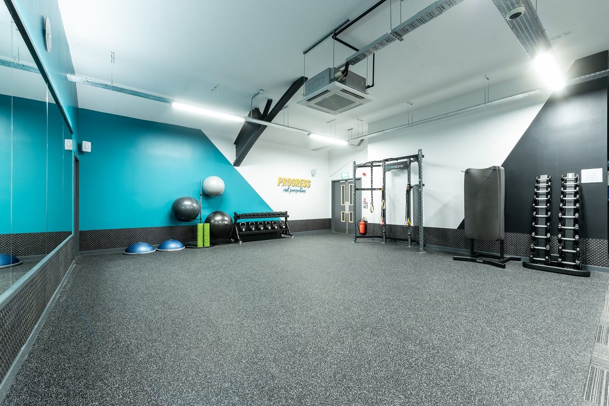 PureGym London Streatham: Resistance machines, free weights, exercise balls, rubberized flooring in teal-coloured studio.