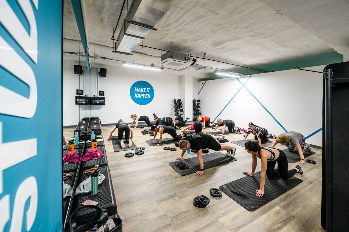 PureGym Hitchin: Weight benches, resistance bands, exercise mats, and people working out on the floor.