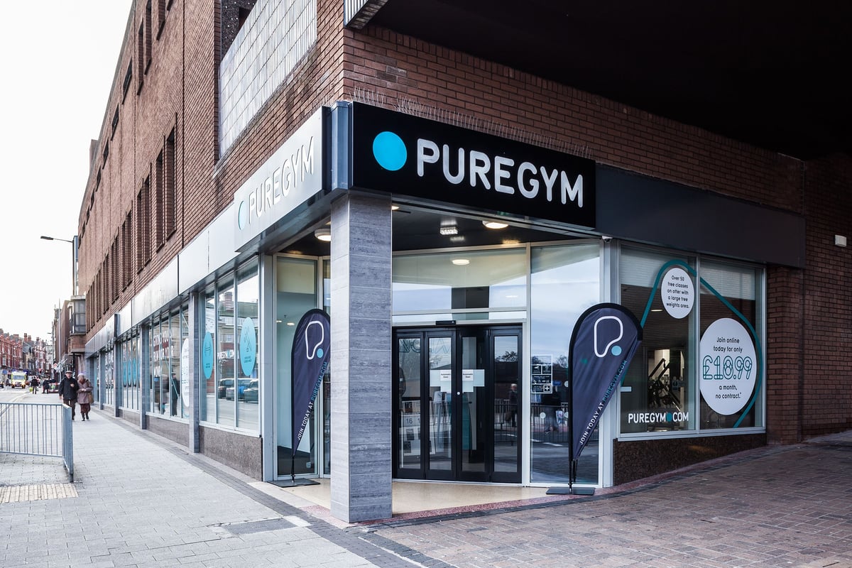 PureGym Altrincham: Signage for PureGym fitness center on exterior of brick building with windows.