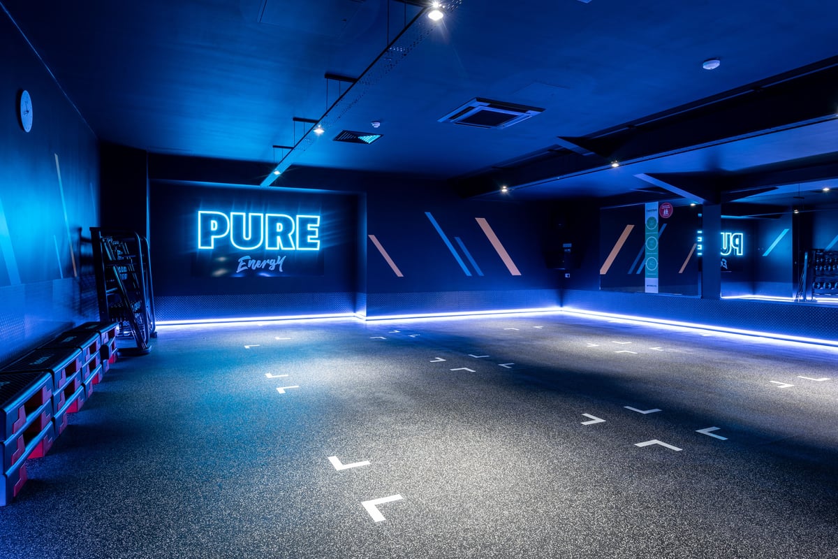 PureGym Plymouth Marsh Mills: Indoor studio space with neon lighting, floor markings, and "PURE" signage visible.