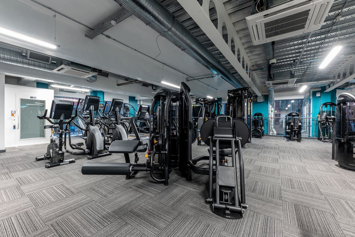 PureGym Manchester First Street: Rows of cardio machines, weight stacks, and resistance equipment in a modern gym setting.