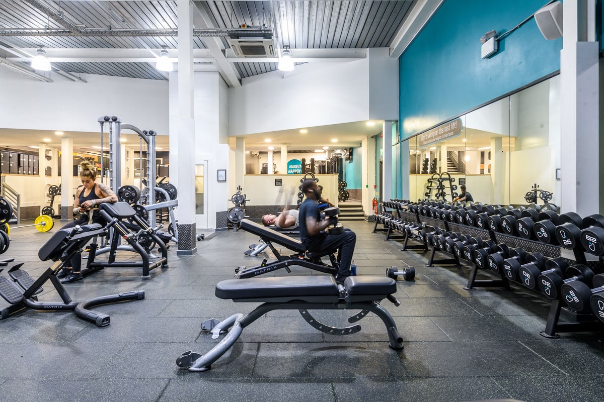 PureGym London Wandsworth: Weight benches, free weights, resistance machines, and rubberized flooring in a gym setting.