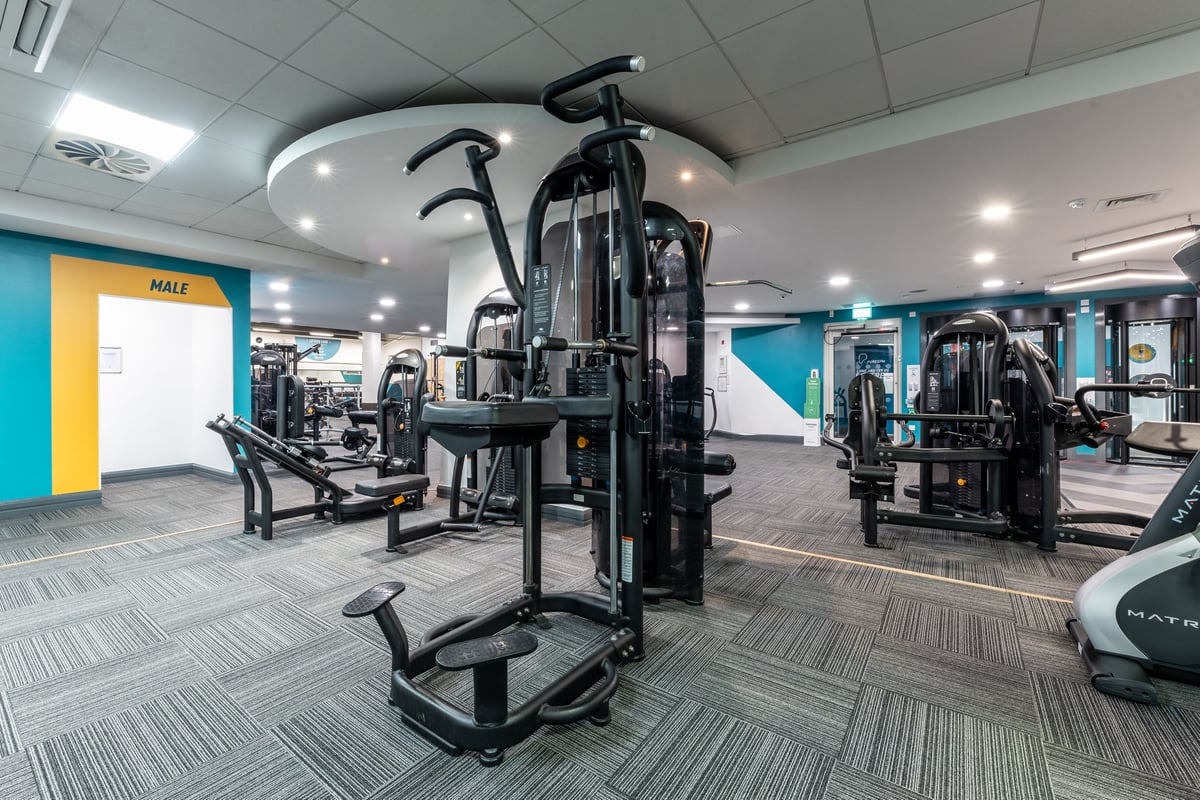 PureGym London Edgware: Rows of strength training machines, weight benches, and rubberized flooring in a gym setting.