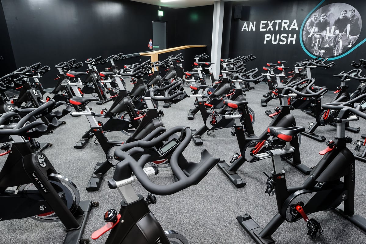 PureGym Glasgow Hope Street: Rows of stationary exercise bikes inside a dimly lit fitness studio.