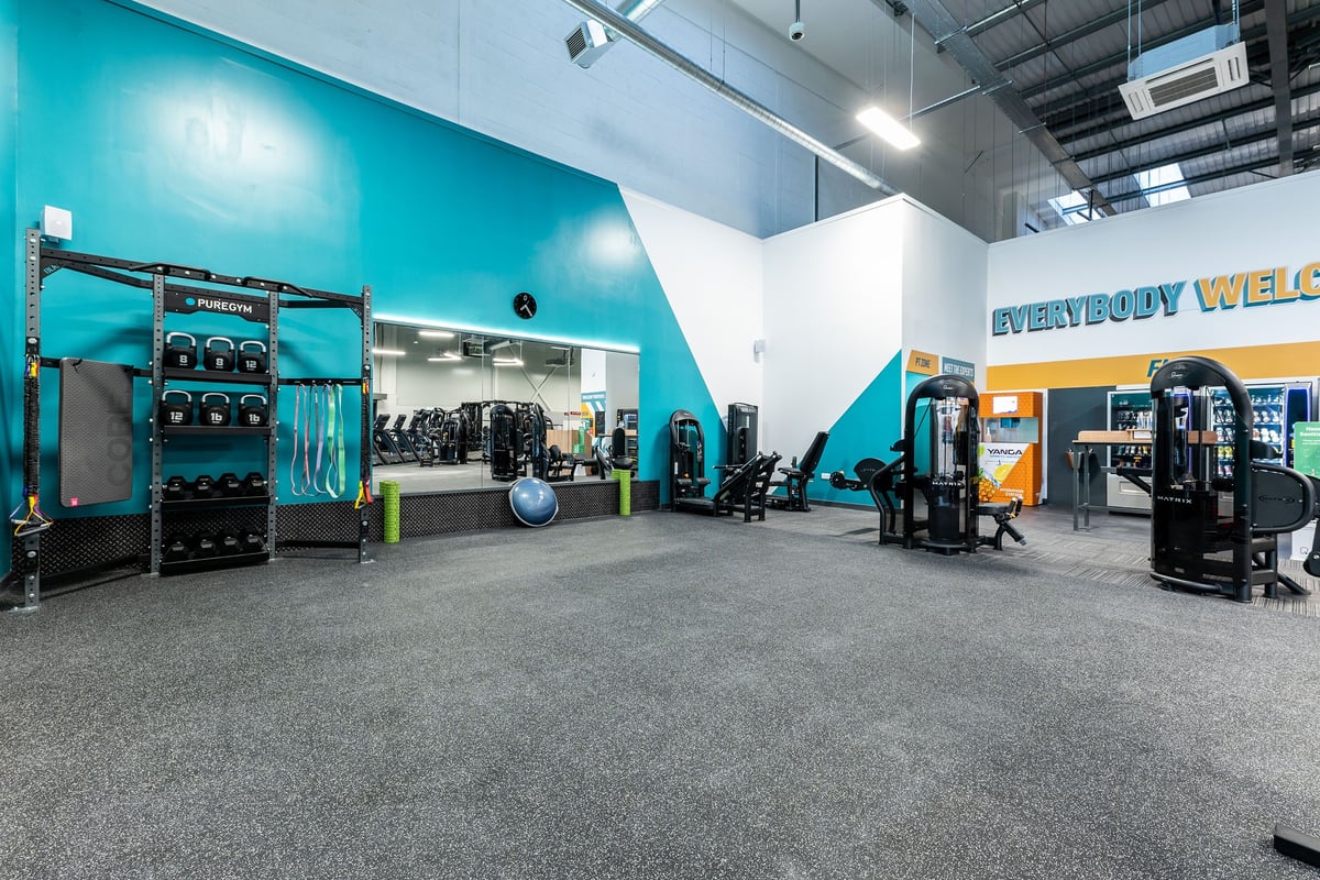 PureGym Kirkby: Resistance machines, weights racks, rubberised floors in bright blue and white fitness studio.