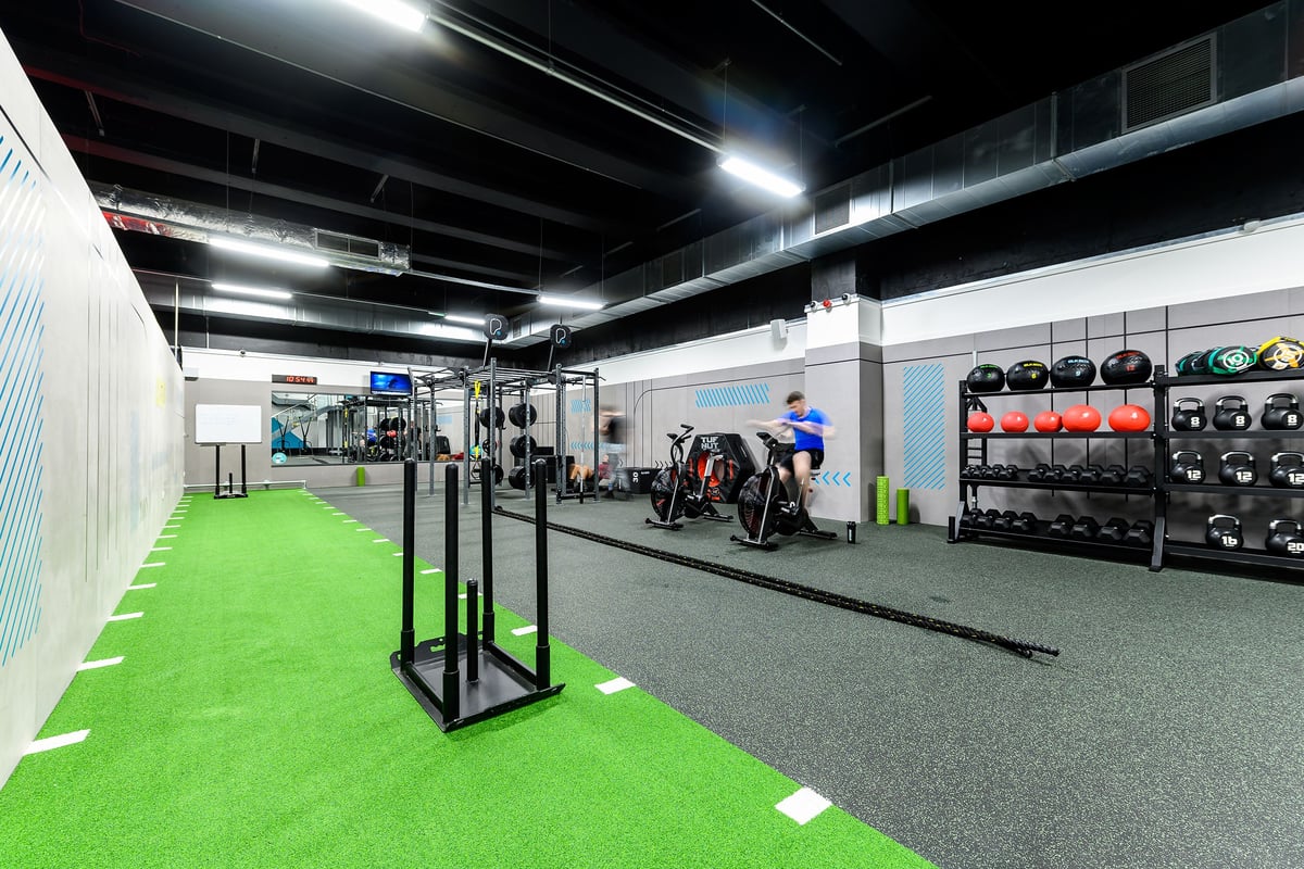PureGym Leeds City Centre North: Workout area with squat racks, weight racks, green turf section, and rubberized flooring.