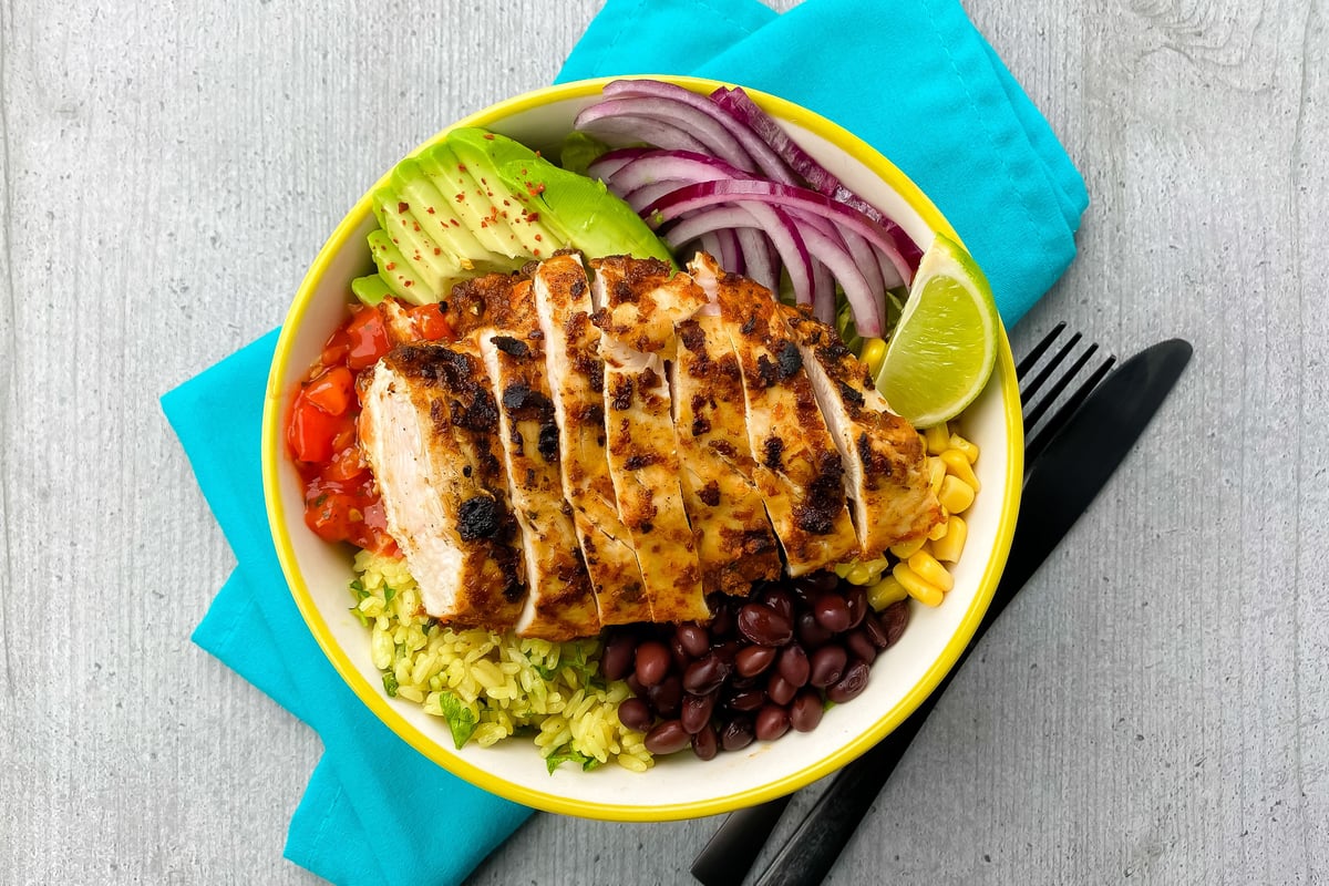 Grilled sliced chicken on rice with black beans, sweetcorn, avocado, red onion and lime
