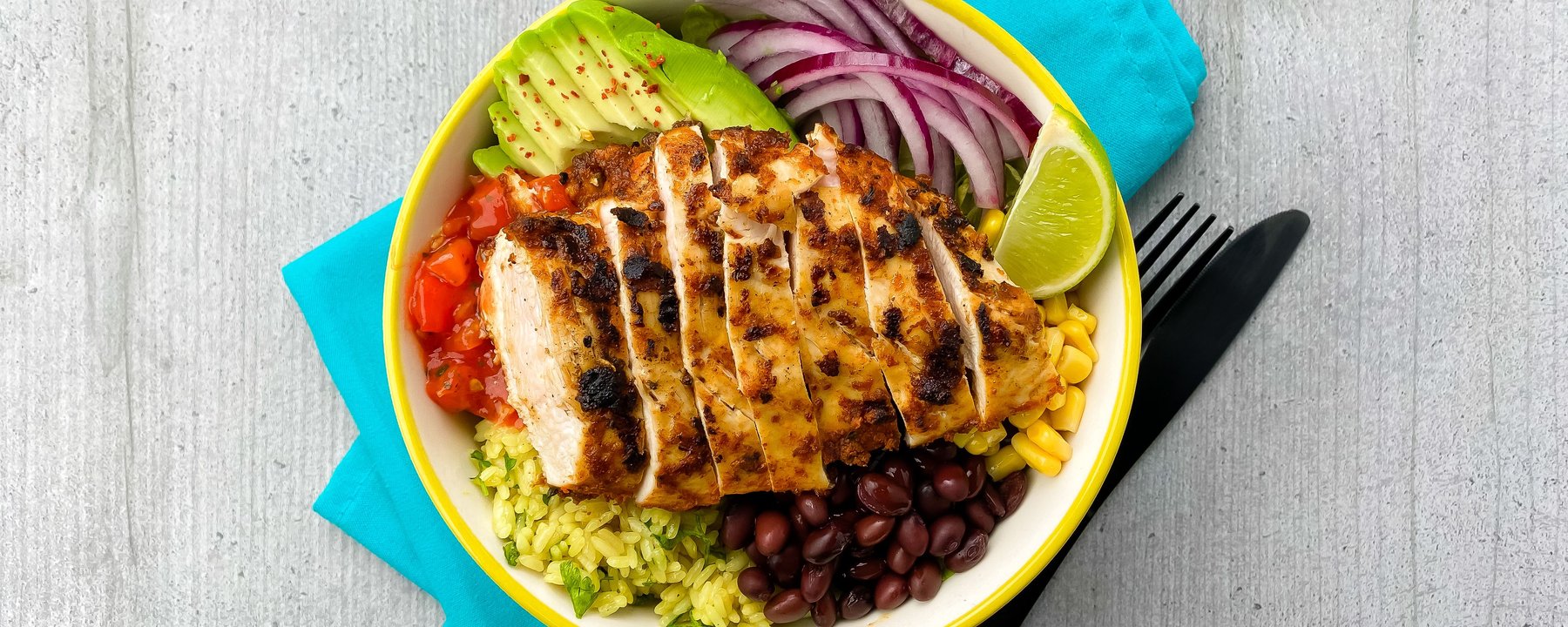 Grilled sliced chicken on rice with black beans, sweetcorn, avocado, red onion and lime