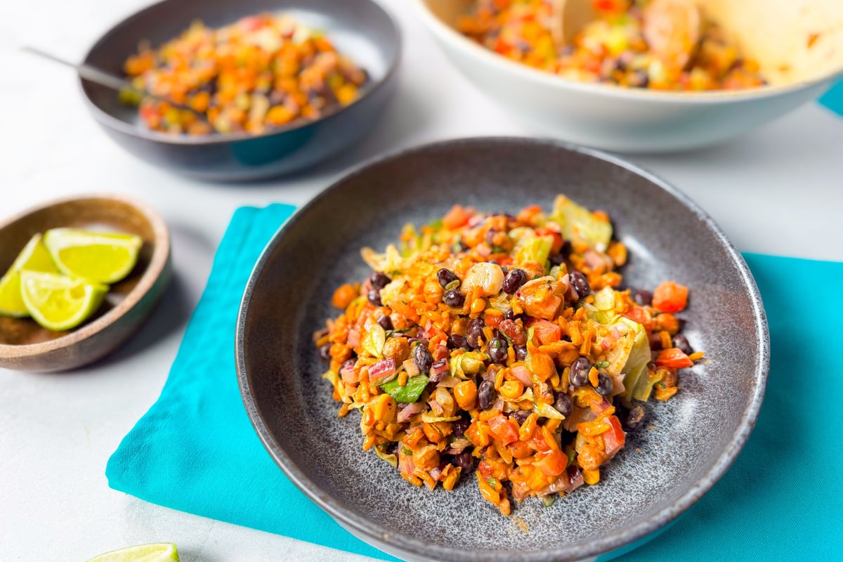 Mixed bean and vegetable salad served in grey bowls with lime wedges on the side