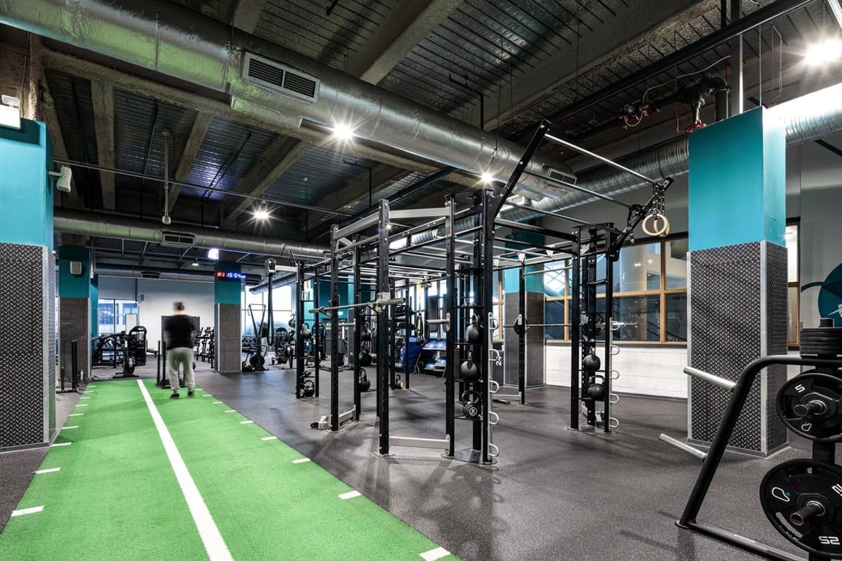 PureGym Cardiff Central: Rig frames, weight racks, green turf section, and rubberized flooring in a gym setting.