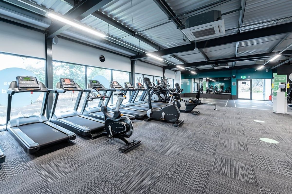 PureGym Kirkcaldy: Rows of treadmills, ellipticals, stationary bikes in a gym with large windows.