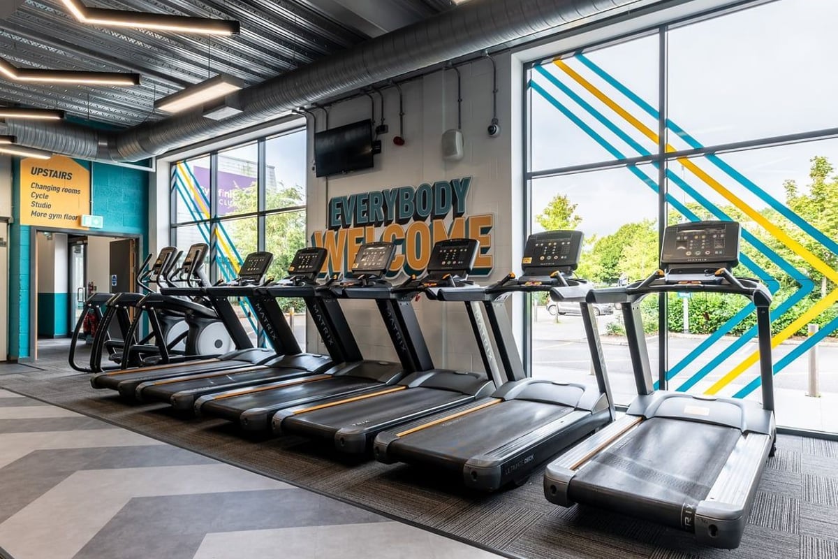PureGym Reading Basingstoke Road: Rows of treadmills, vibrant geometric wall art, and signage saying "Everybody Fit Out".