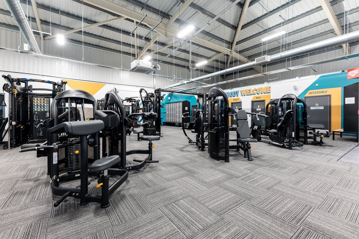 PureGym Merthyr Tydfil: Resistance machines, weight racks, benches and patterned rubber flooring in a spacious gym area.