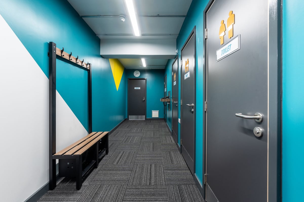 PureGym London Hornchurch: Gym corridor with benches, cubbies, and exercise images on walls.