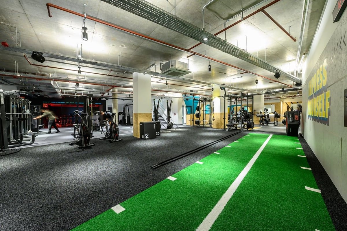 PureGym London Fulham: Weightlifting area with squat racks, functional training turf, free weights, and rubberized flooring.