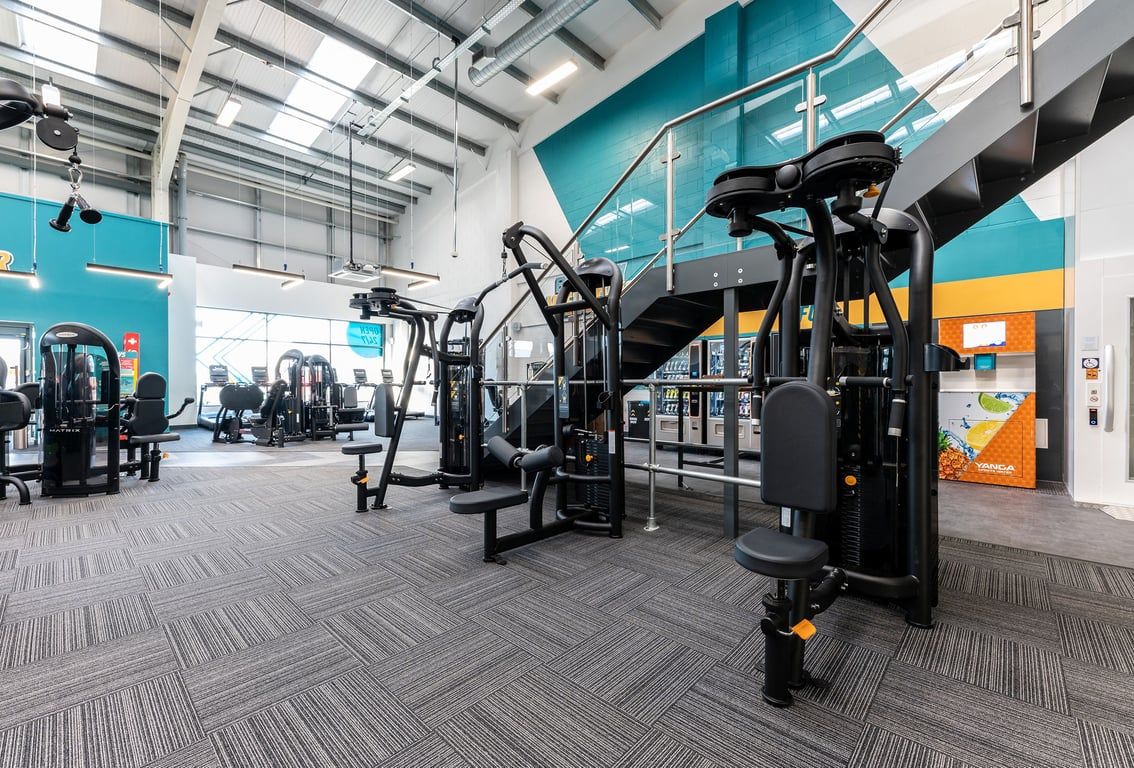 PureGym Consett: Weight machines, resistance equipment, rubberized floors in a spacious gym facility.