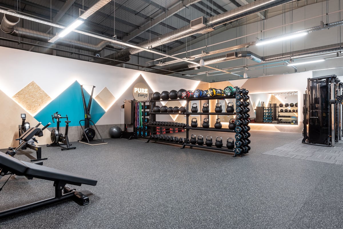 PureGym Harwich: Workout area with strength equipment, free weights, benches, and rubberized flooring.