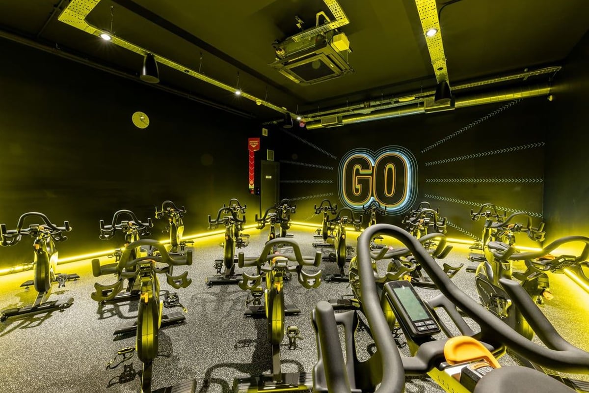 PureGym Tamworth: Stationary bikes, electronic displays, neon lighting in a cycling studio.