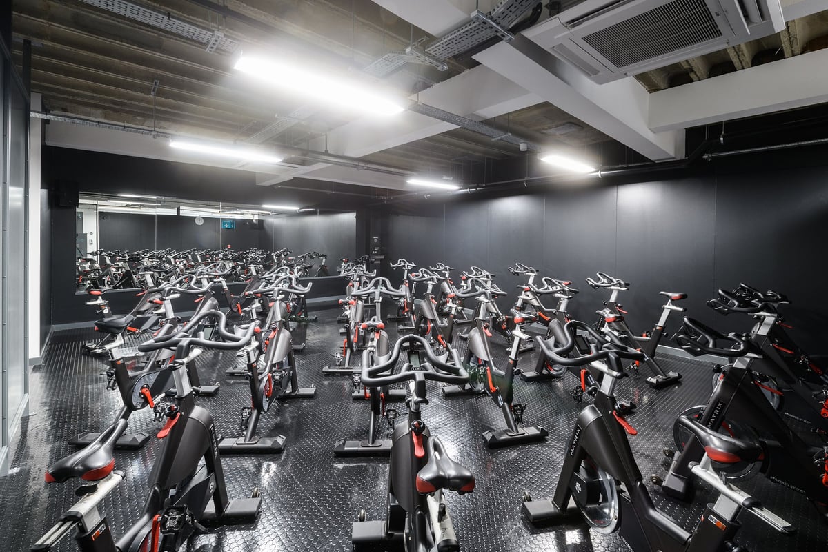 PureGym Brighton London Road: Rows of stationary exercise bikes inside a dimly lit studio with industrial ceiling.