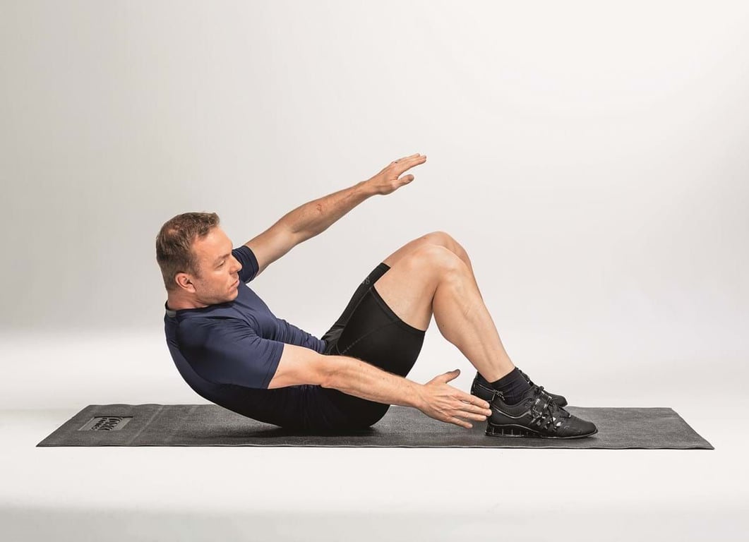 Man exercising on mat doing Russian twists with bent knees and arms extended