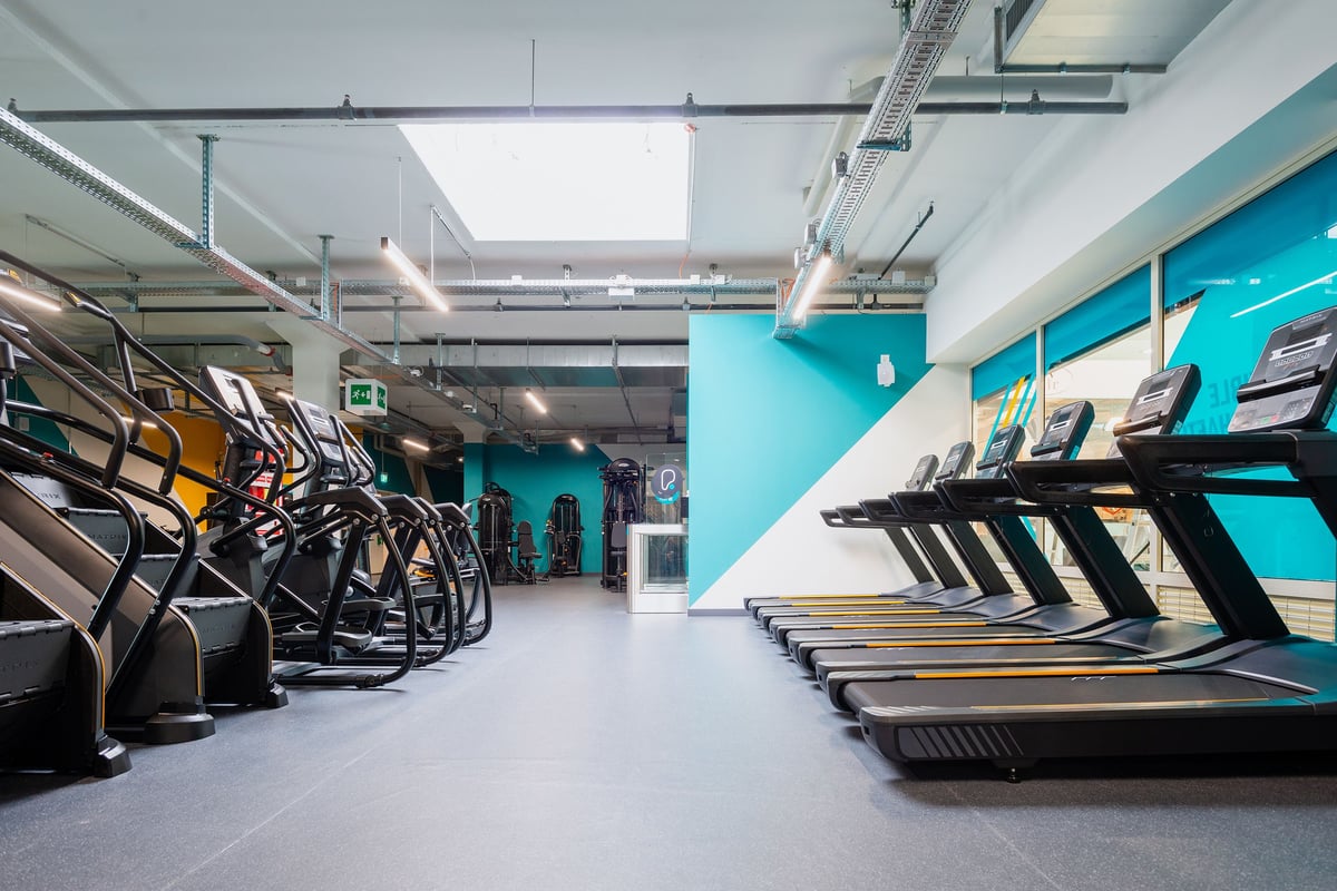 PureGym Wil: De longues rangées de tapis roulants, de vélos elliptiques et de monte-escaliers aux murs colorés.