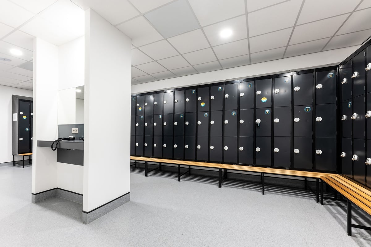 PureGym Livingston: Rows of lockers, benches underneath, minimal decor gym changing room.
