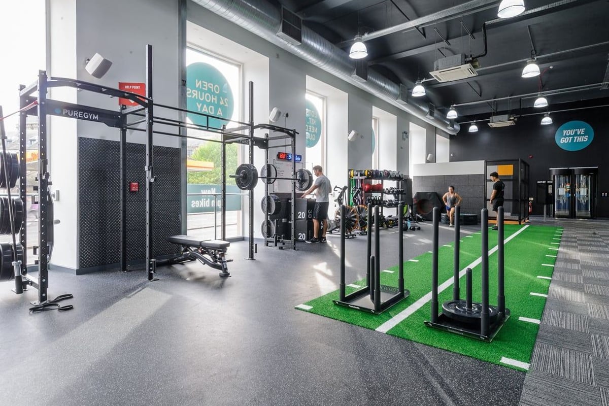 PureGym Dundee: Free weights, squat racks, turf training area, and rubberized flooring in a gym setting.