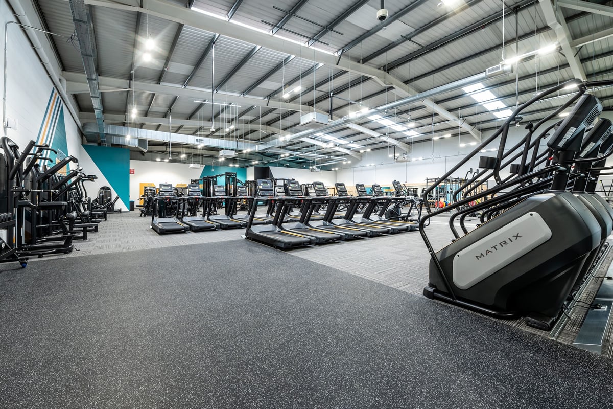 PureGym Newbury: Rows of treadmills, ellipticals, and other cardio machines in a large gym space with high ceilings.