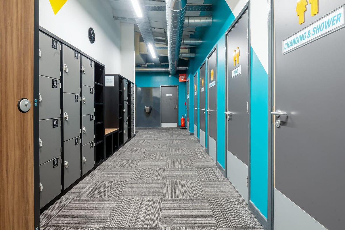 PureGym Linlithgow: Changing room lockers, shower stalls, patterned tiled floor.