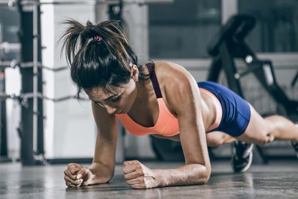 Woman in sportswear doing a plank exercise on a gym floor