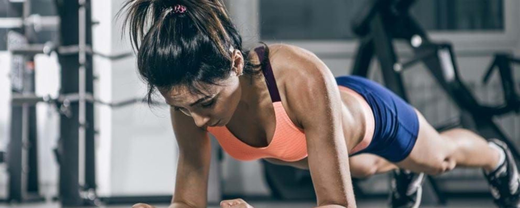Woman in sportswear doing a plank exercise on a gym floor