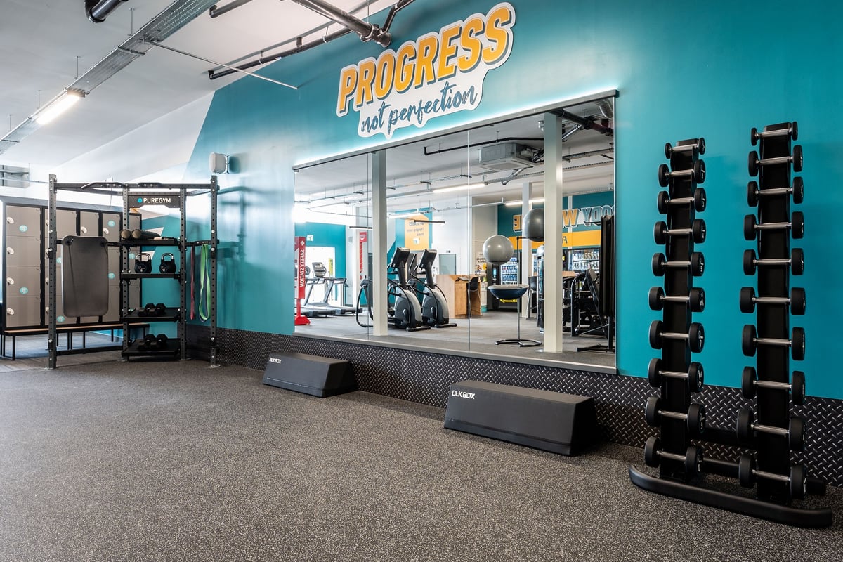 PureGym Sittingbourne: Resistance machines, free weights, rubberized flooring in a teal and yellow fitness studio.