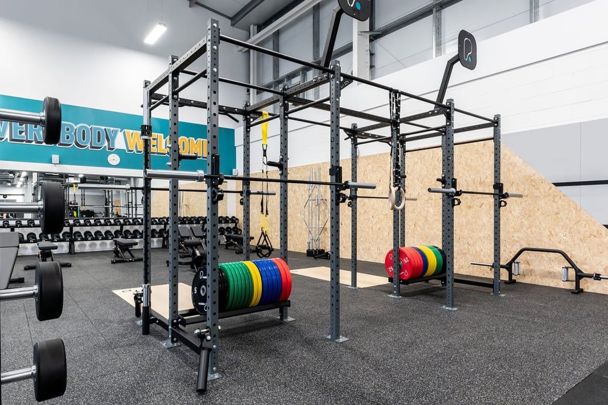 PureGym Galashiels: Power racks, barbell setups, bumper plates, and rubberised flooring in a weight training area.